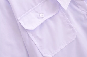 Detailed macro view of the chest pocket and button on this white V-neck commuter shirt