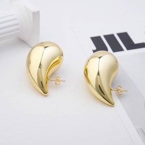 Macro view of 18K gold-plated teardrop earrings with a polished surface on white props
