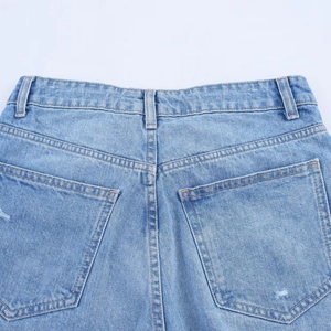 Close-up of blue denim jeans showing rear waistband, pockets and twill fabric texture