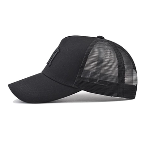 Close-up of black cotton baseball cap showing breathable mesh and embroidered M logo