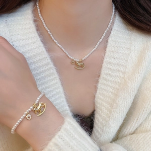 Detailed view of pearl necklace and bracelet set with golden horse pendants on a model