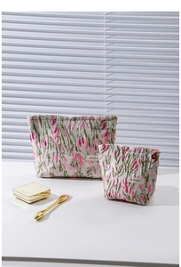 Close-up of cream fabric makeup bags with pink tulip embroidery and zipper detail