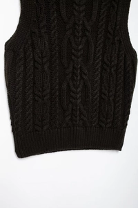 Detailed macro view showing cable knit patterns and ribbed hem of the warm sweater vest