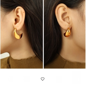 Close-up of golden exaggerated teardrop earrings on a model with a polished finish
