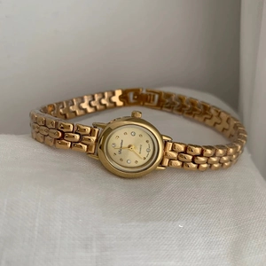 Elegant gold quartz bracelet watch for women with round diamond-accented dial on white fabric