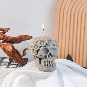 Artistic skull-shaped scented candle with floral carvings on white silk fabric