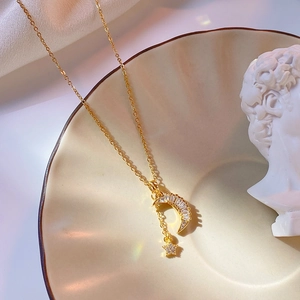Elegant gold moon and star tassel necklace with zircons displayed on a ceramic tray