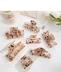 Flat lay of diverse tortoiseshell hair claws with floral and newspaper props