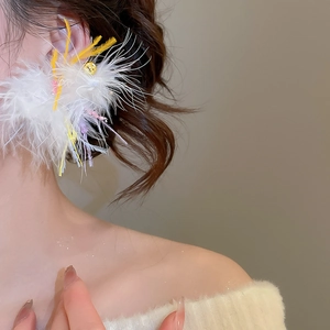 Detailed view of white fluffy feather earrings with colorful accents on a model