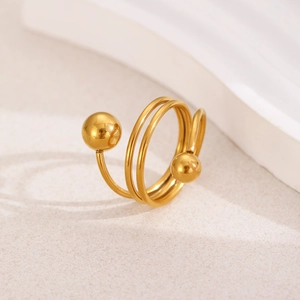 Macro shot of gold spiral ring with polished beads on a minimalist cream background