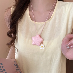Dettaglio della collana con stella rosa, ciondolo a margherita e cordino su modella