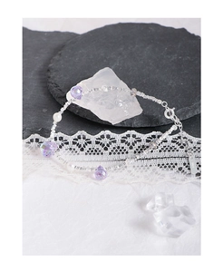 Macro detail of S925 silver bracelet featuring purple crystals and white pearls on lace