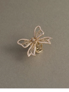 Detailed close-up of golden metal butterfly hair claw with pearls and hollow design