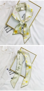 Detail of light green floral skinny silk scarf shown tied and flat on white shirt