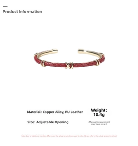 Dettaglio del bracciale aperto in pelle intrecciata rossa con decorazioni in metallo dorato a X