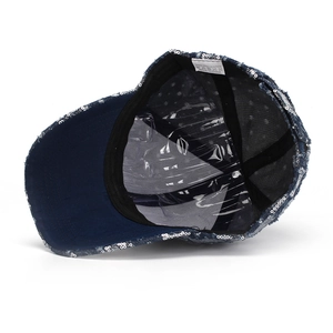 Close-up of the denim baseball cap interior featuring silver sequins and a 100% polyester label