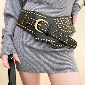 Detail of vintage black leather belt with gold metal studs and large buckle on knit dress