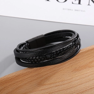 Close-up of men's multilayer leather bracelet with black feather charm and magnetic clasp