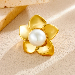 Detailed view of a golden vintage flower ring with a large white pearl on a textured surface