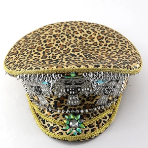Leopard print captain hat with silver studs, gold chains and green gemstone flower