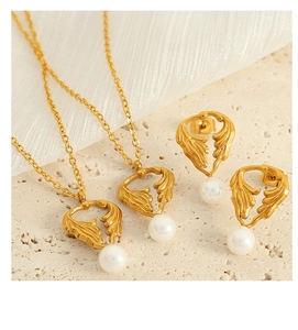 Detailed view of gold leaf necklaces and pearl earrings on a natural stone surface