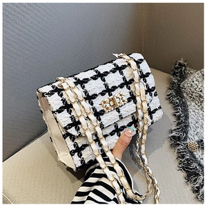 Close-up of black and white tweed texture and gold chain strap on stylish shoulder bag