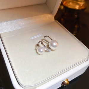 Close-up of twisted gold plated earrings with pearls and zircons in a jewelry box