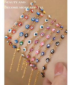 Detailed view of multiple gold evil eye bracelets with colorful enamel charms on model wrist