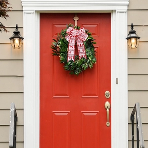 Fiocco natalizio rosso con renne appeso a una ghirlanda festiva verde decorativa
