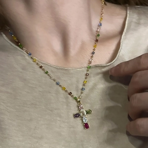 Détail du collier croix dorée avec zircons colorés et perles assorties sur la chaîne