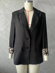 Detail of women's black blazer showing leopard print cuffs and double-breasted buttons