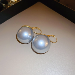 Vue détaillée de boucles d'oreilles perles grises avec fermoir doré sur surface texturée