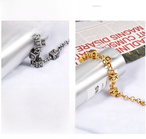 Detail of silver and gold titanium steel bracelets featuring Lucky lettered metal cube beads