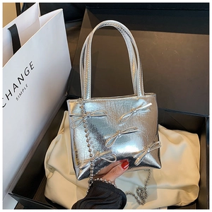 Close-up of silver bow handbags with metallic leather texture in a gift box packaging