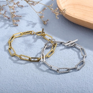 Detail of gold and silver industrial chain bracelets with OT toggle clasps on a blue surface