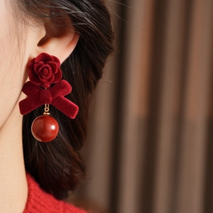 Detailansicht von vintage roten beflockten Rosen- und Bogenohrringen am Modell