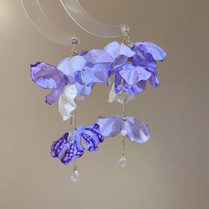 Detail of purple fabric flower earrings with crystal tassels and gold chain on stand