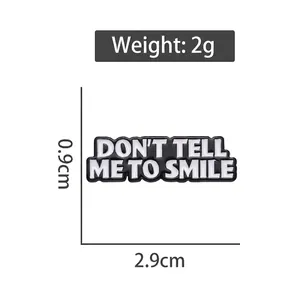 Rectangular black enamel pin with DON'T TELL ME TO SMILE text and 2.9cm size dimensions