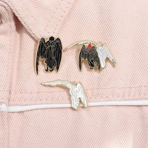 Set of three black and white angel and demon enamel pins on a pink denim jacket