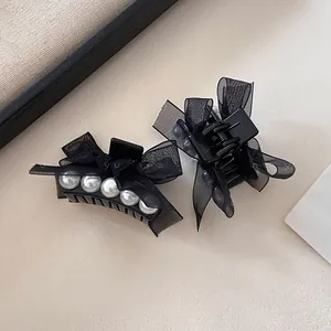 Detailed view of elegant black mesh bow hair clips with white pearls in French style