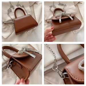Detail view of brown mini bag with rhinestone bow ornament and silver chain strap