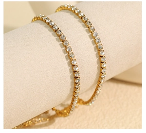 Gros plan de deux bracelets tennis dorés avec zircons pavés sur un support beige