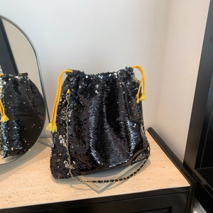 Detail of black sequined bucket bag with yellow drawstring and metal chain strap