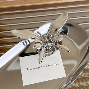 Silver butterfly metal hair claw clip displayed on a tray for elegant half-up hairstyles