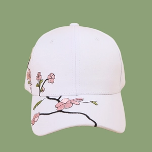 Close-up of pink flower embroidery on a white cotton baseball cap with a curved brim
