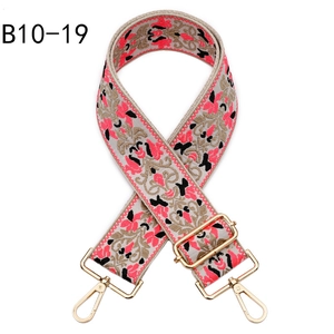Detail of ethnic jacquard purse strap with pink floral embroidery and gold metal clasps