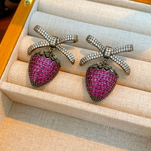 Macro shot of strawberry earrings with zircon bowknot in a beige jewelry box