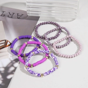 Detail of bohemian purple heishi clay and crystal beaded bracelet stack with gold spacers
