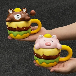 Cartoon hamburger ceramic mugs with cute bear and pig lids shown held in hands