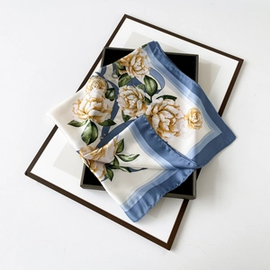 Detailed flat lay of a satin floral square scarf with blue border and yellow flowers